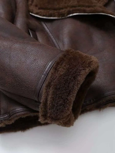 Detailed macro of dark brown faux shearling jacket with premium leather zipper finish