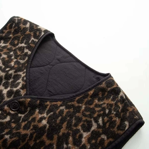 Detail of leopard print faux fur vest featuring quilted lining and black button closure