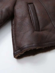 Close-up of faux leather jacket featuring plush brown fur lining and side pocket detail
