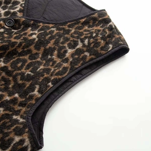 Detail of leopard print padded vest featuring quilted black panels and matte button
