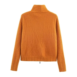 Macro shot of orange knitted cardigan detail showing ribbed cuffs and soft plush texture