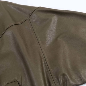Detail view of deep olive green faux leather texture and reinforced stitching on jacket