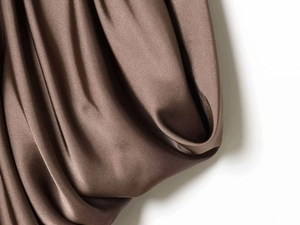 Detail of premium brown satin fabric showing smooth texture and elegant drapes