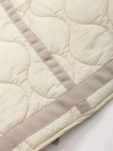 Macro detail of wave quilted texture and ribbed trim on a beige winter cotton coat
