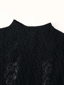 Detail of black semi-high neck romper with textured plush fabric and delicate lace trim