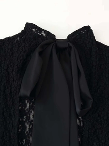 Close-up of elegant black lace neckline featuring a premium satin bow decoration