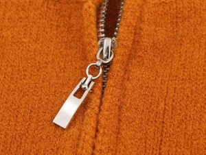 Detailed macro view of orange thick knit texture and modern silver double metal zipper