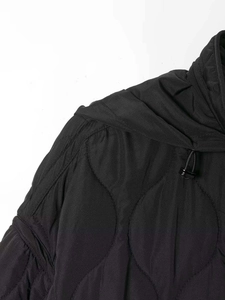 Close-up of black quilted winter jacket featuring wavy stitching and adjustable drawstring