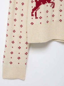 Close-up of winter knit sweater showing red reindeer jacquard and snowflake patterns