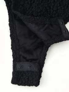 Close-up of black faux shearling romper showing snap button closure and plush texture