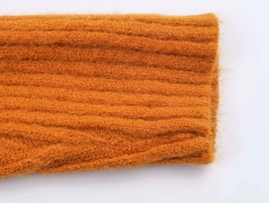 Detailed macro view of amber orange knit cardigan with ribbed cuffs and soft wool texture