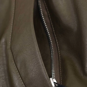 Close-up of olive brown faux leather jacket showing fine texture and silver metal zipper