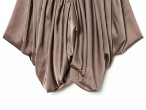 Detailed close-up of dark brown satin fabric showing elegant drapes and glossy silk texture