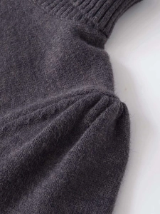 Detail of dark charcoal knit sweater showing soft texture and pleated shoulder design