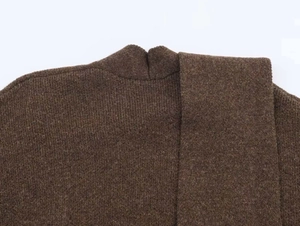 Vista dettagliata della trama del maglione marrone e sciarpa coordinata sulla spalla
