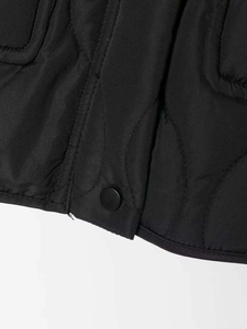 Detailed view of wave-quilted black fabric with matte metal snap button closure