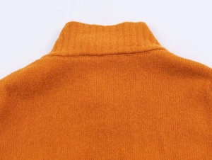 Close-up of the ribbed turtleneck and fine knit texture of this dark orange sweater