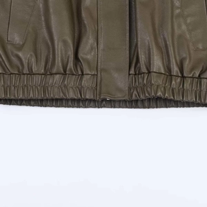 Detailed macro view of the elasticated hem and leather texture on an olive brown jacket