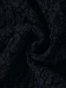 Macro shot of black textured honeycomb lace fabric with intricate 3D floral details