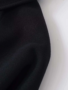 Macro shot of black woolen fabric showing thick texture and dense weave detail