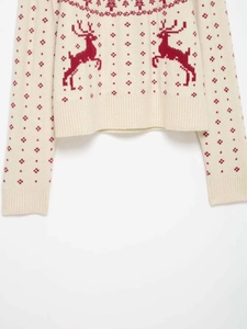 Detailed knit texture of Christmas sweater with red reindeer and snowflake jacquard patterns