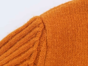 Detailed close-up of bright orange ribbed knit fabric texture and shoulder seam stitch