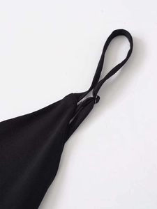Detail view of thin straps and high-quality stitching on a black asymmetric dress