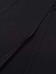 Detailed close-up of the asymmetric slit and neat stitching on a black summer dress