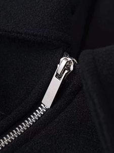 Close-up of silver metal zipper and textured black wool fabric on cropped jacket