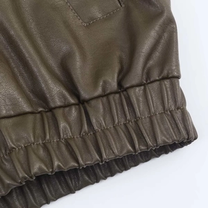 Detail view of deep olive green faux leather jacket with elastic hem and fine stitching