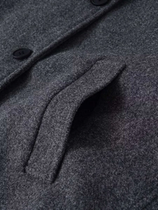 Détails macro de la veste en laine gris foncé montrant la texture et les boutons en résine