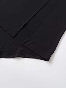 Detail of double-needle stitching and irregular hem on a black summer slip dress