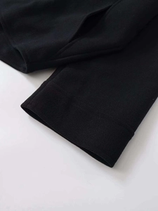 Detail of a black wool jacket featuring a side pocket and brushed texture stitching