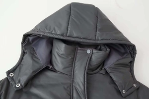 Detail of winter padded coat showing drawstring hood and matte metal snap buttons
