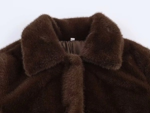 Detail shot of the large lapel and dense faux fur texture on the brown winter coat