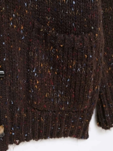 Détail de gilet en maille tweed marron avec bouton marbré et texture de poche plaquée