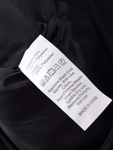 Detailed close-up of the wash care label showing 100% polyester fabric on a black jacket
