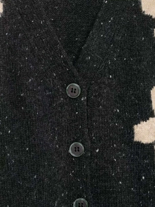 Detailed macro view of dark grey floral jacquard knit cardigan texture and buttons