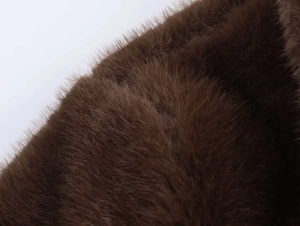 Close-up of deep brown faux fur texture showing soft dense fibers for winter outerwear