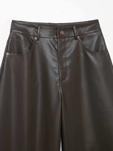 Dettaglio dei pantaloni in ecopelle marrone scuro con rivetti in rame e tasche classiche