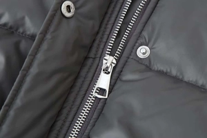 Macro shot of high-quality silver metal zipper and snap buttons on black winter coat
