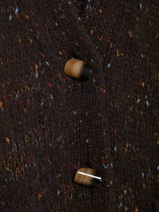 Détail de la maille en tweed marron foncé avec boutons cylindriques marbrés