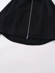 Detail of silver metal zipper and curved hem on black short woolen jacket