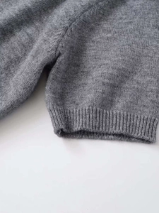 Detailed macro view of gray knit sweater showing fine ribbed texture and soft wool fabric