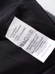 Gros plan sur l'étiquette d'entretien indiquant 100% polyester et consignes de lavage