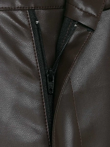 Dettaglio macro dei pantaloni in ecopelle marrone scuro con chiusura a zip robusta