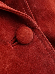 Detail of red suede jacket showing fabric texture and fabric-covered button with stitching