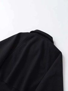 Detailed view of black wool coat shoulder with raglan sleeve and clean stitching