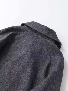 Détail d'un manteau en laine gris montrant coutures d'épaules et texture du tissu