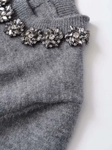 Close-up of grey knit top featuring intricate floral crystal beadwork along the neckline